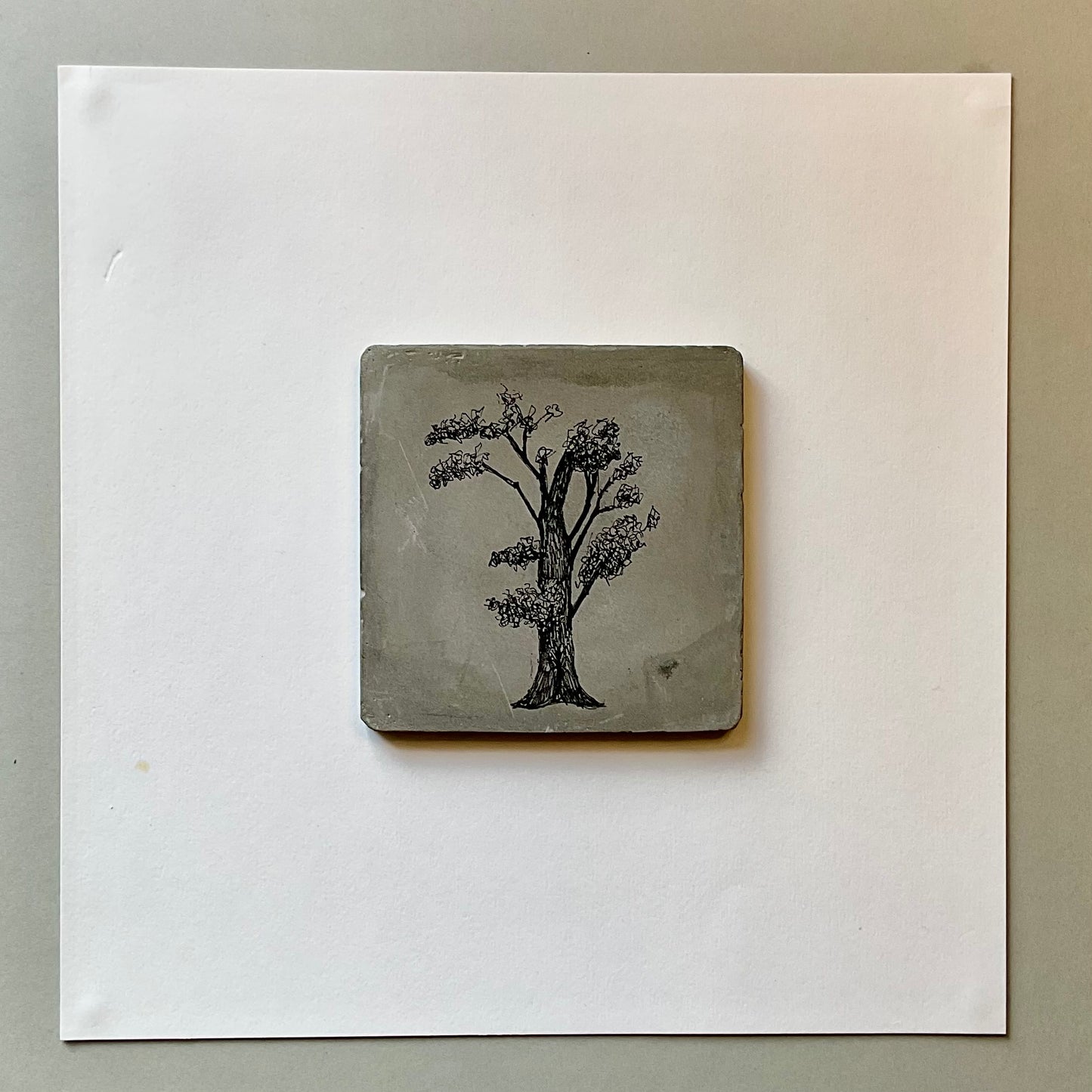 Original ink tree drawing on a square grey cement tile with branching canopy and fine-line detail.