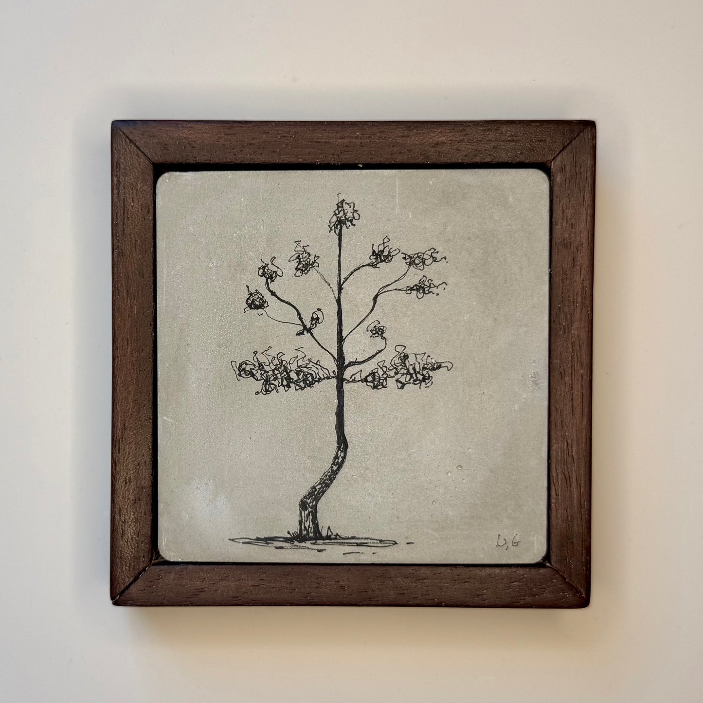 Framed artwork of a tree on a cement tile