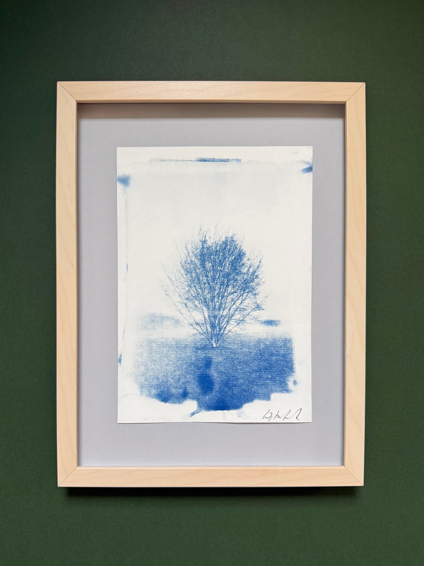 Framed original handmade cyanotype of a solitary tree on Hackney Marshes, London, presented in a light wood frame with a grey mount.