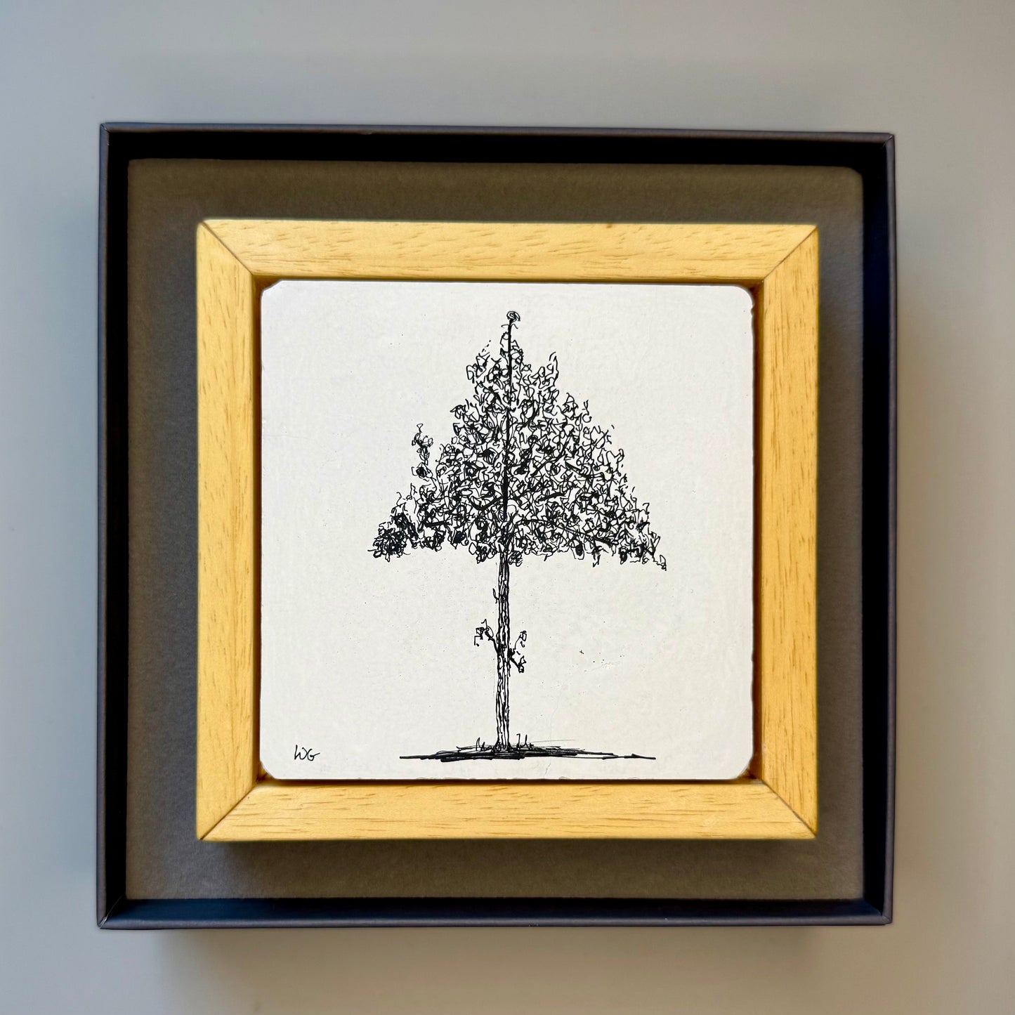 Framed black and white drawing of a tree on a plain background in a box