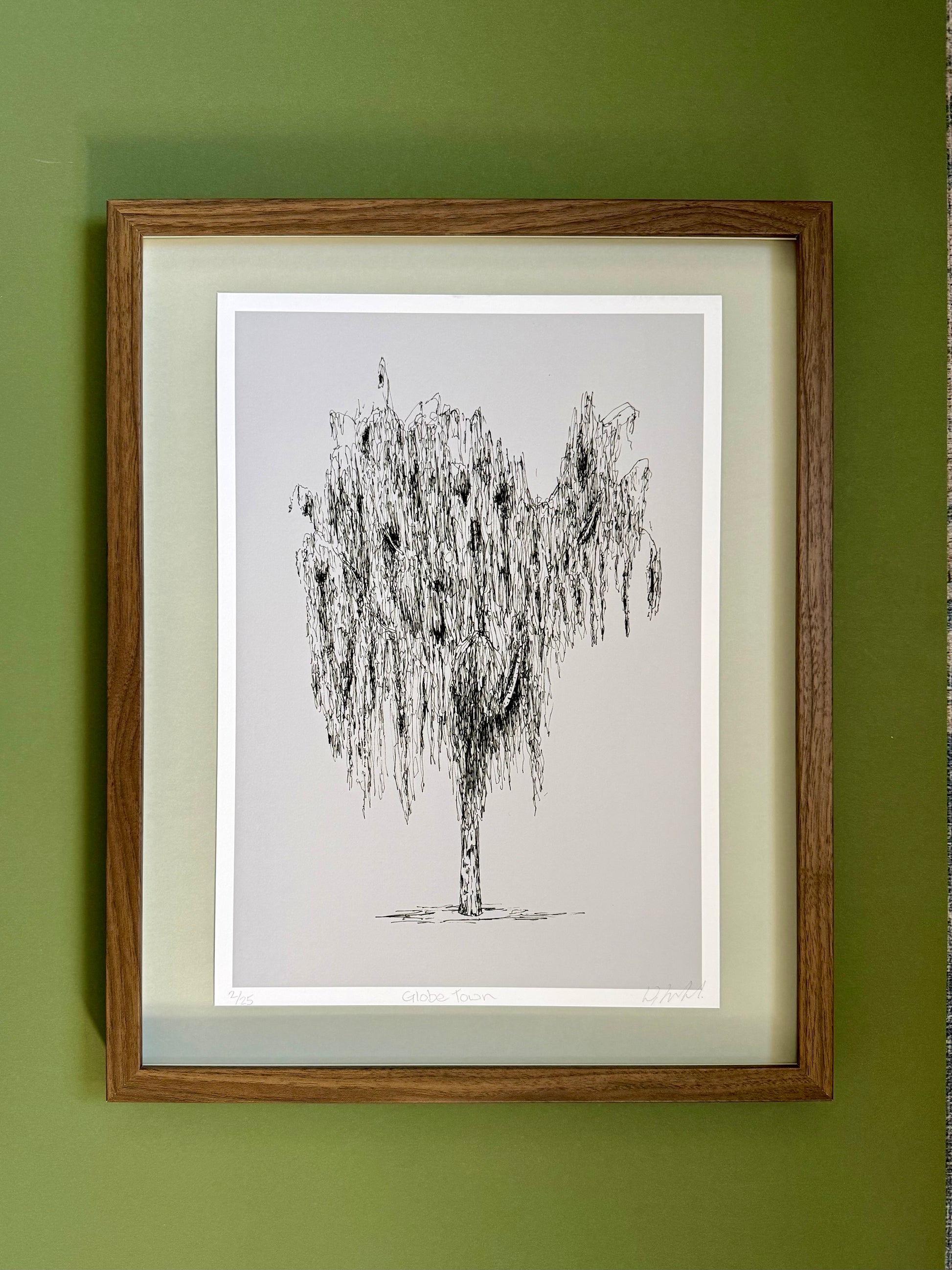 Framed black and white tree drawing on a green wall