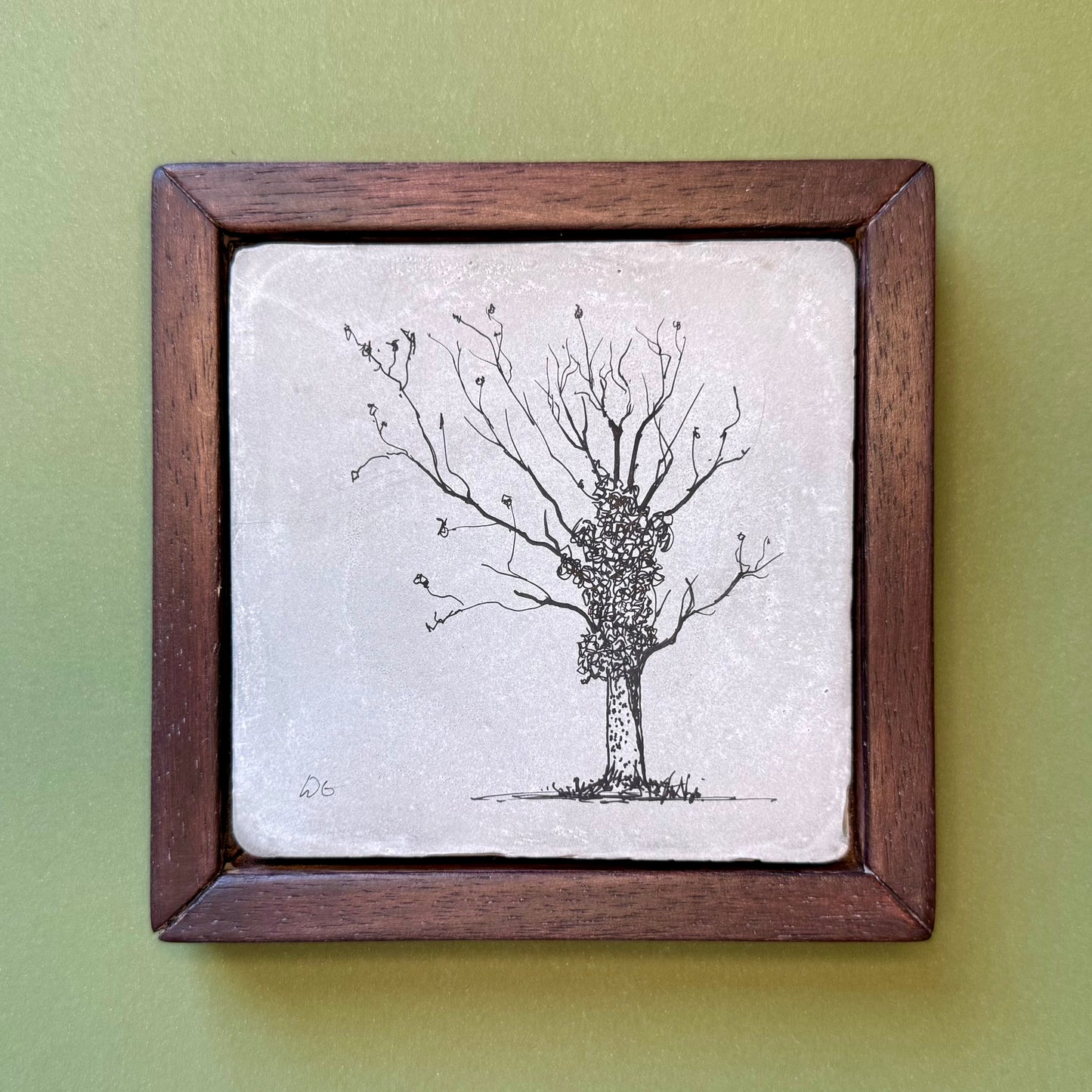 Framed artwork of a tree on a textured surface with a wooden frame against a green background