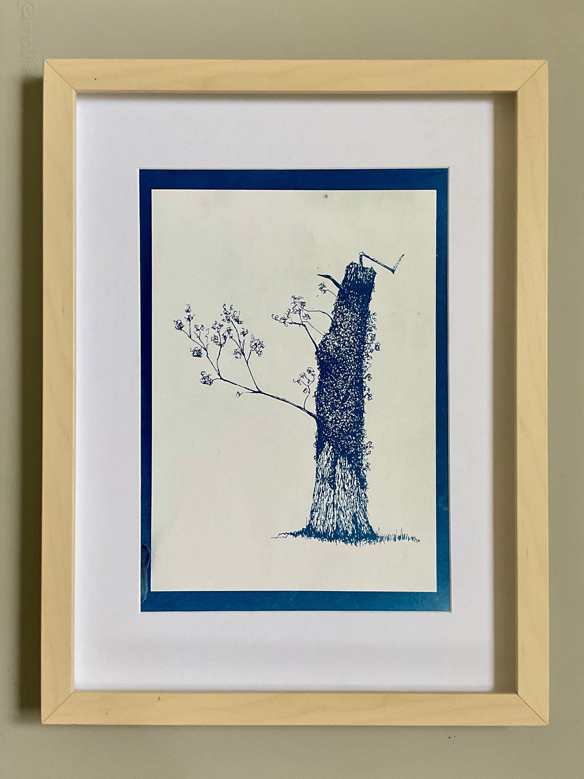 Framed cyanotype of a leaning tree in positive print — dark blue ink drawing on a light background, created using a handmade traditional cyanotype process.