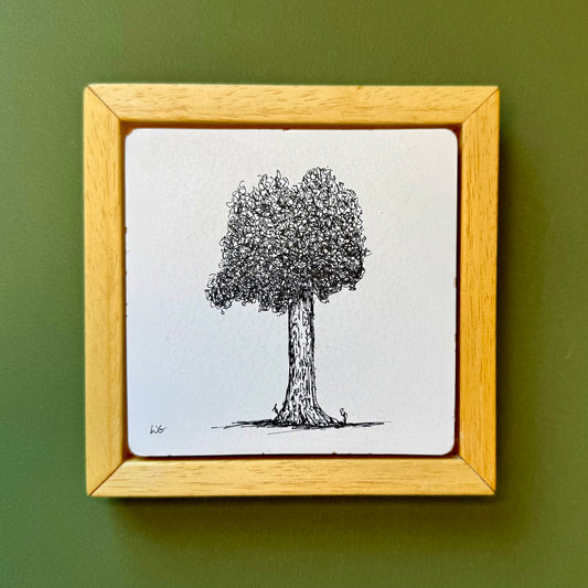 Framed drawing of a tree on a white background with a wooden frame against a green wall.
