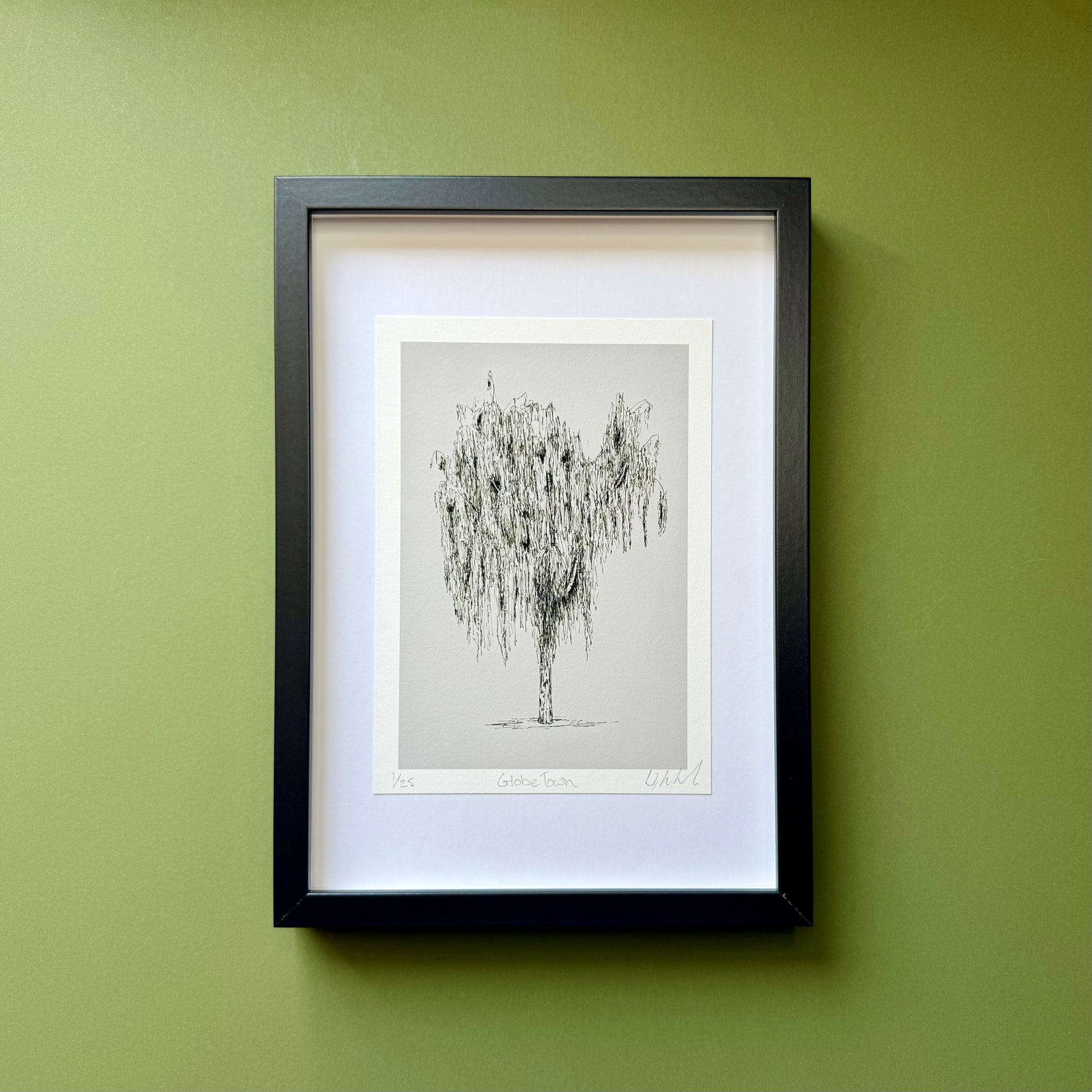 Framed artwork of a tree on a green wall