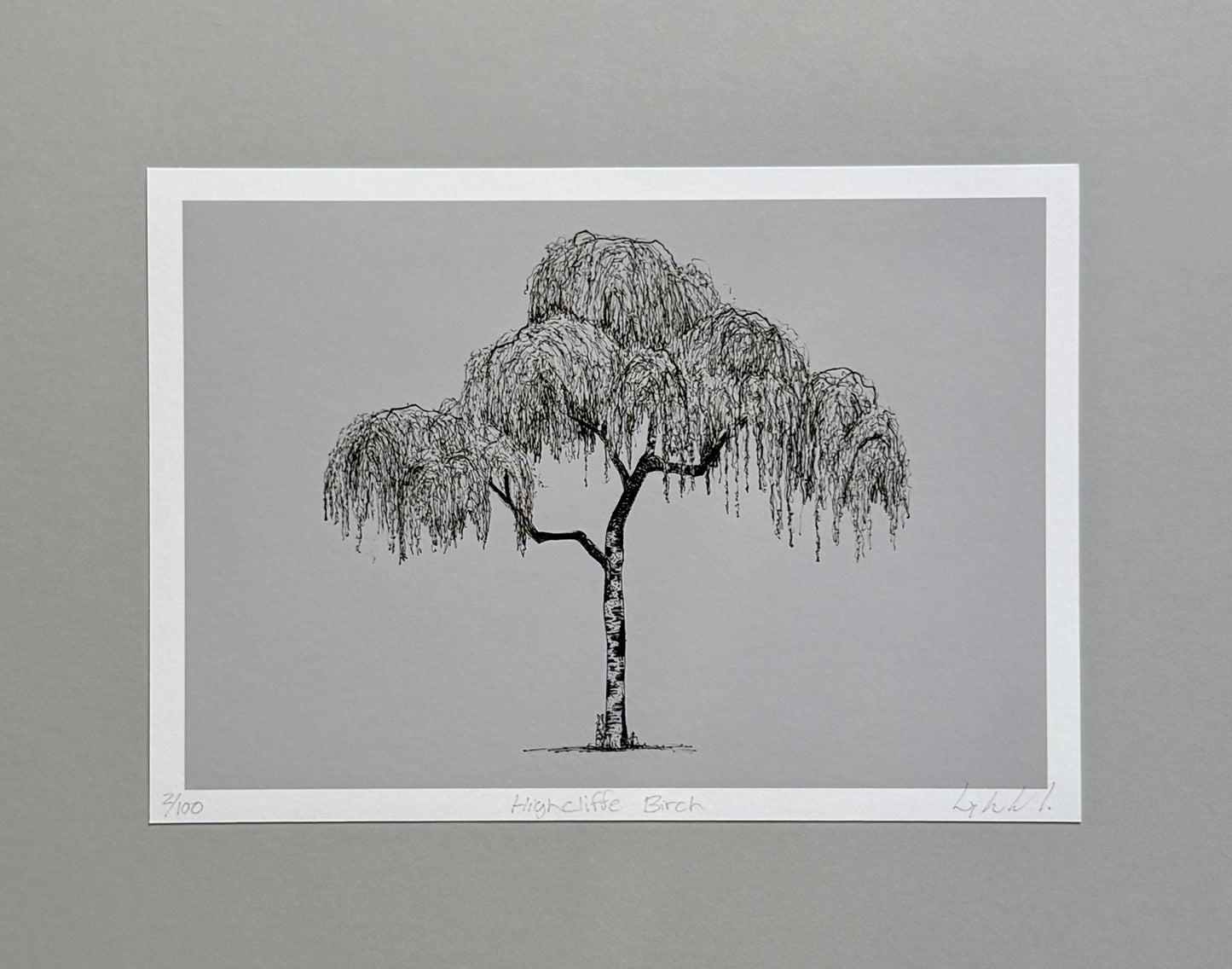 A minimalist black and white art print of a weeping willow tree, presented on a white paper sheet against a neutral gray background.