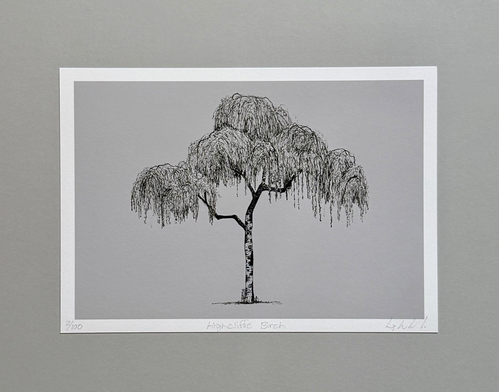 A minimalist black and white art print of a weeping willow tree, presented on a white paper sheet against a neutral gray background.