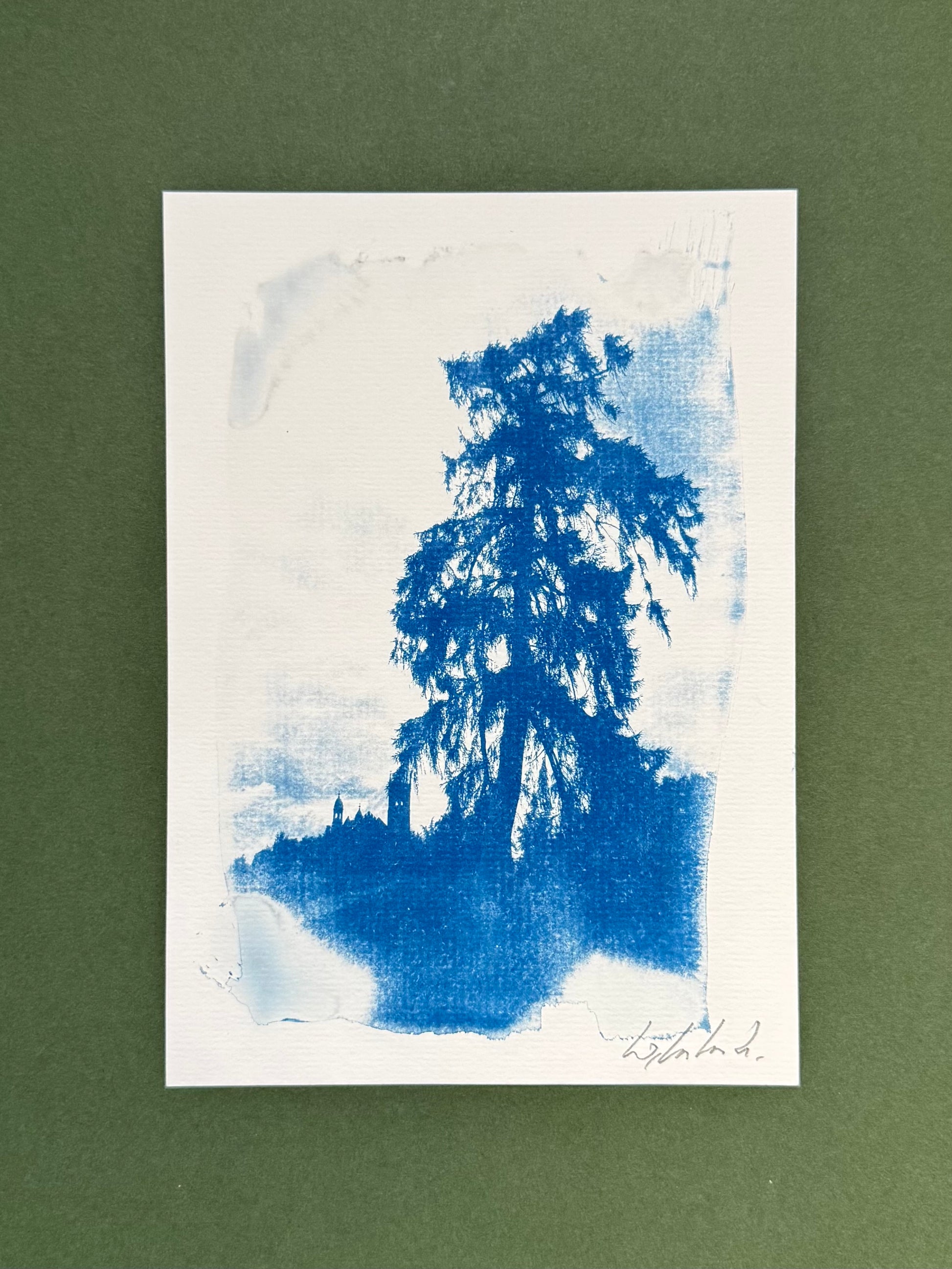 A vertical art print featuring a blue ink or watercolor tree silhouette on a white paper background, set against a solid dark green backdrop.