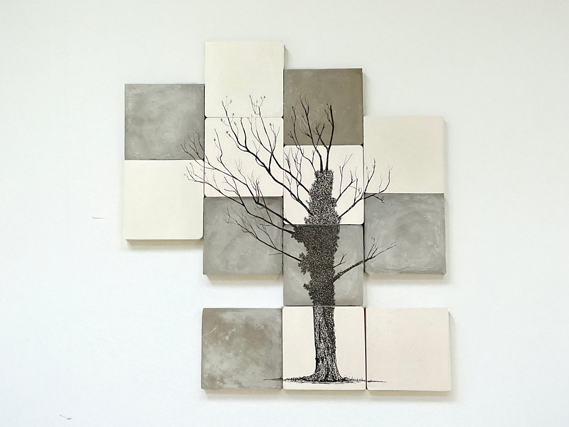 Ink drawing of an ivy-covered oak tree illustrated across twelve hand-cast cement tiles in tones of grey and white.