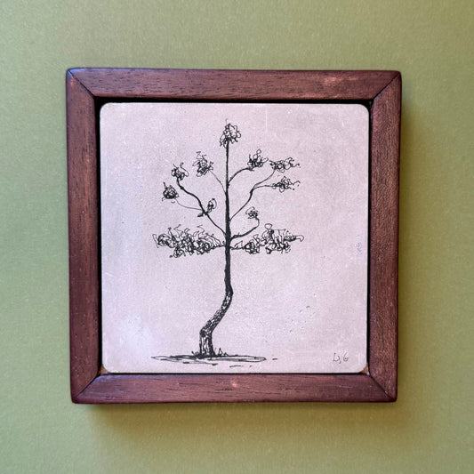 Framed artwork of a tree on a cement tile
