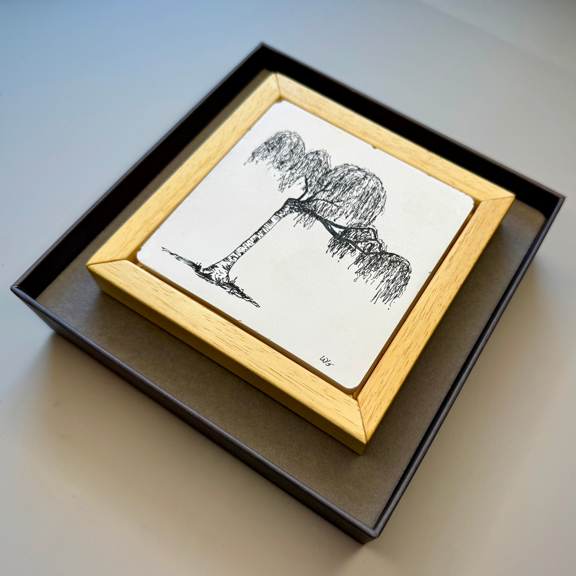 Framed black and white tree illustration on a light surface