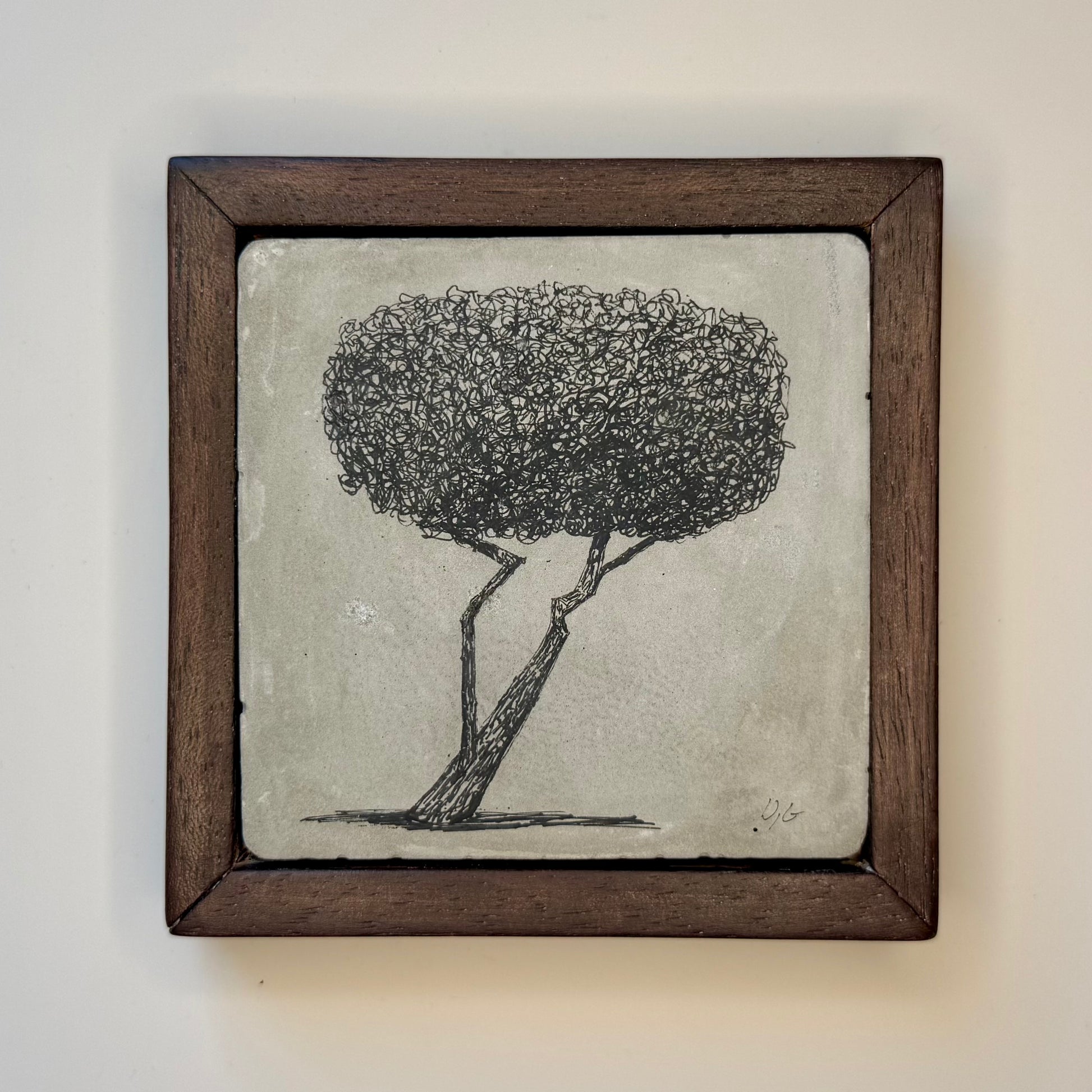 Framed artwork of a tree on a textured surface with a wooden frame.