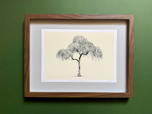 A framed art print featuring a black ink sketch of a weeping tree on a cream background, matted with white and enclosed in a medium brown wood frame, mounted on a textured dark green wall.