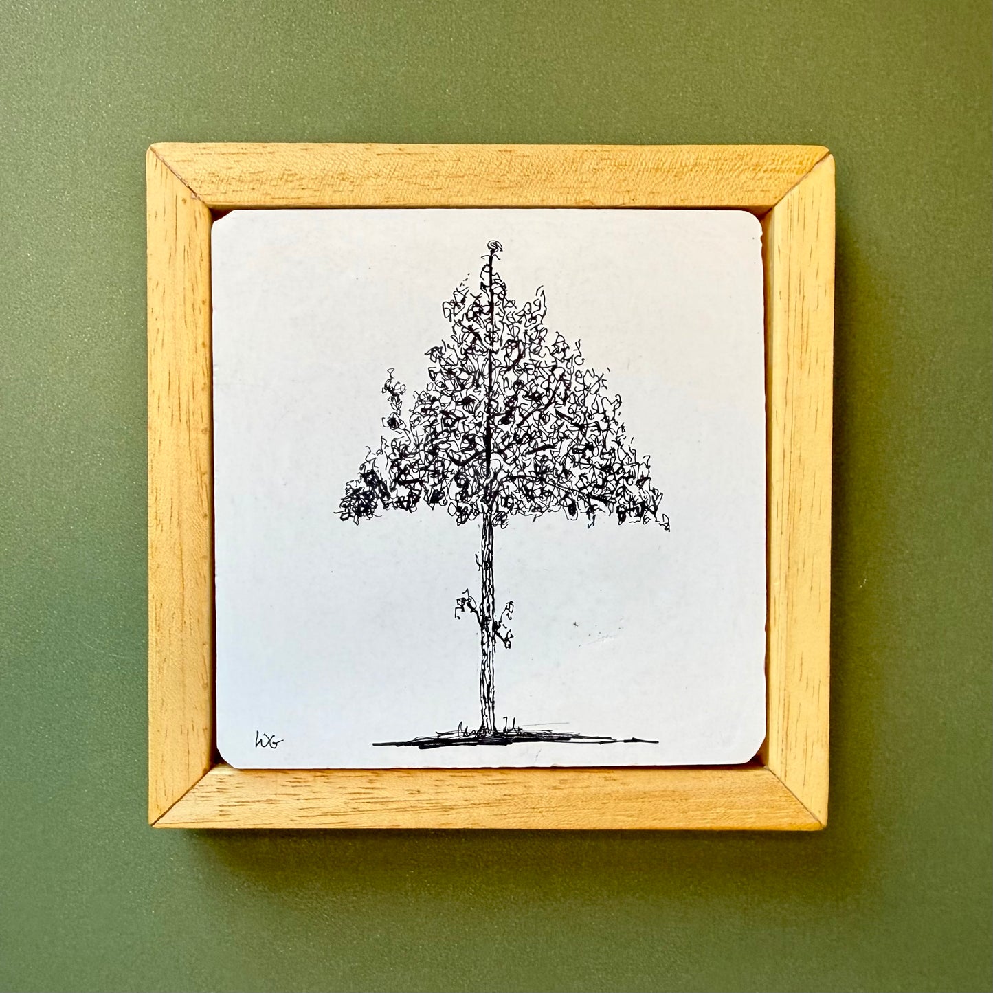 Framed black and white tree drawing on a green wall