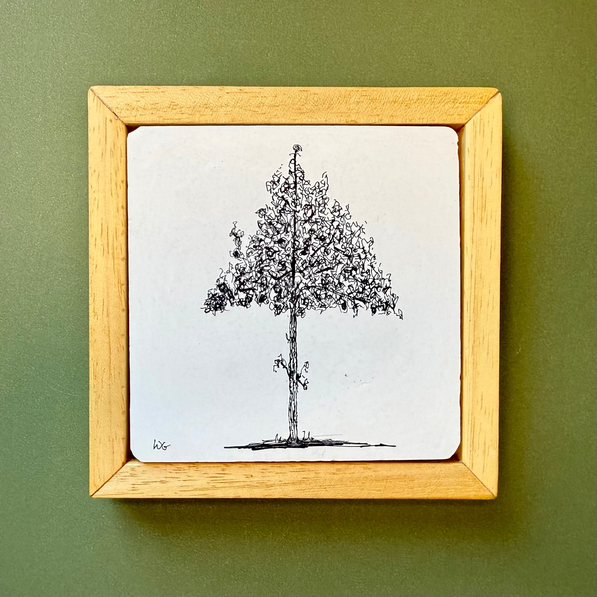 Framed black and white tree drawing on a green wall