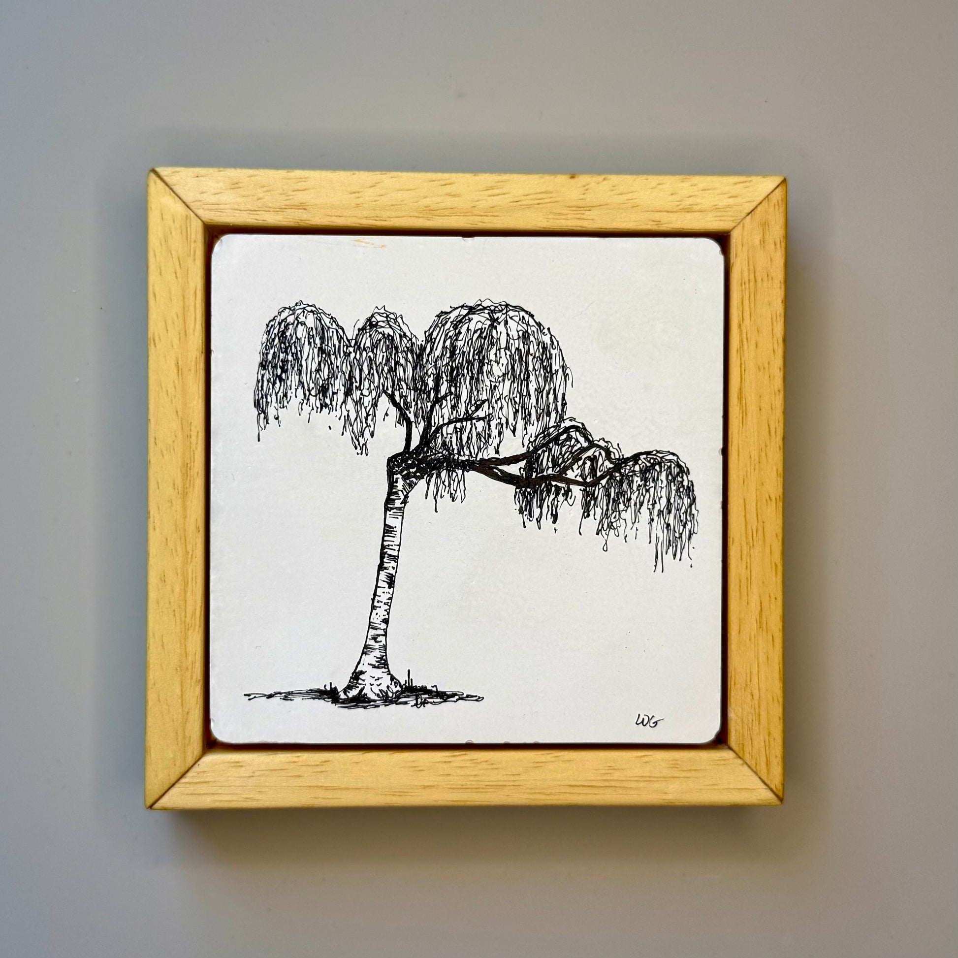 Framed artwork of a black and white tree on a gray wall