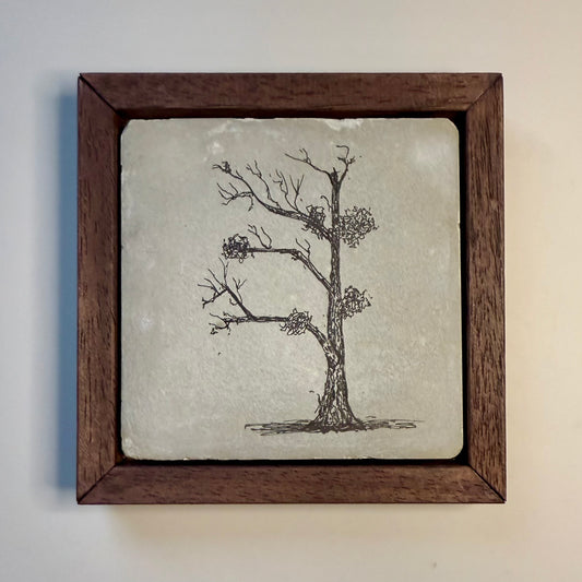 “Framed ink drawing of a bare tree with clusters of mistletoe by Warren Garland, drawn on a hand-cast cement tile and set in a dark wood frame.”