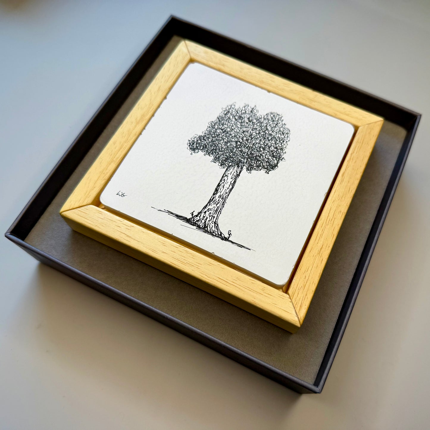 Framed black and white illustration of a tree on a plain background