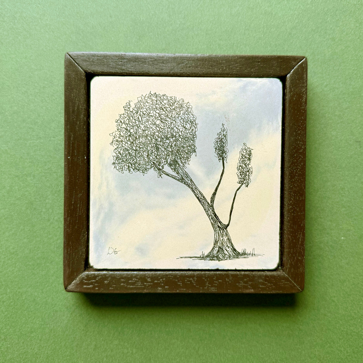Original black ink drawing of a tree in the Malvern Hills, with an asymmetric leafy canopy and two slender upright branches. Drawn on hand-cast pigmented Portland cement with subtle blue and cream tones, presented in a dark wooden frame against a green background.